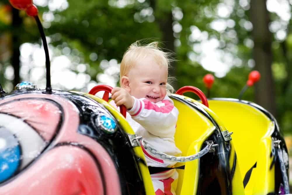 A toddler enjoying a kiddie ride at a theme park.