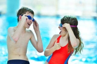 happy children with swim goggles at indoor swimming pool